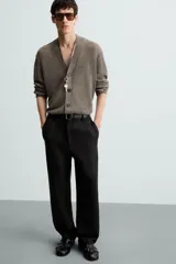 Pantalón de vestir color blanco hueso, de corte recto y tiro medio, con cintura elástica y cierre frontal de botón y cremallera. Presenta bolsillos frontales y bolsillos traseros de vivo.