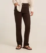 Pantalón slim de jeans color marrón, con cintura media, cierre tradicional con cremallera y botón, trabillas en la cintura, bolsillos delanteros y traseros con encaje.