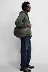 Bolso de hombro color marrón oscuro fabricado en piel con acabado craquelado. Tiene un compartimento principal con cierre de cremallera y un bolsillo interior con cremallera.