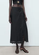 Falda midi negra con detalle de bordado calado en el ruedo y diseño cruzado.