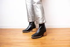 Botas de cuero negro con tacón cuadrado de madera, diseño moderno y elegante.