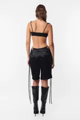 Conjunto de top y short color beige confeccionado en tela brillante. El top cuenta con arco metálico en el busto, tiras para atar en el hombro y ganchos lenceros en la espalda. El short es de tiro alto con cintura elastizada y bolsillos laterales.