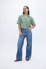 Blusa verde con escote en V, cuello camisero, manga corta y dos bolsillos en el pecho.