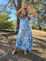 Vestido largo de seda color celeste con estampado floral y paisley en tonos azules, celestes y verdes. Tiene escote en V y mangas cortas.