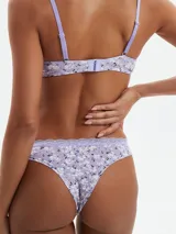 Conjunto de lencería color lila con estampado de pequeñas flores blancas, compuesto por un corpiño con aro y encaje en el borde superior de las copas, y una bombacha tipo bikini con encaje en la cintura.