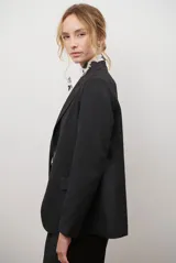 Blazer azul de jean textil, con solapa clásica, un botón frontal y bolsillos laterales.