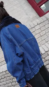 Campera de jean azul con corte oversize, solapa de corderito y pin decorativo.