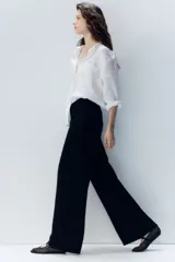 Camisa blanca de lino con cuello clásico, abotonada al frente, de manga larga con puños abotonados, canesú en la espalda, bolsillo de parche en el pecho y bajo redondeado.
