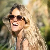 Lentes de sol con montura redonda de madera color marrón claro con diseño de vetas. Lentes color marrón degradado y patillas de madera color marrón claro.