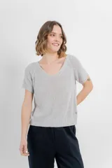 Remera tejida de manga corta, color gris claro, con escote en V y calce relajado. Presenta terminaciones acanaladas en mangas y ruedo.
