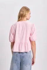 Blusa rosa con rayas verticales blancas, escote redondo con lazos decorativos, mangas cortas abullonadas y corte peplum.