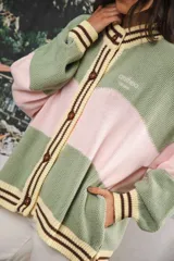 Cardigan tejido a rayas horizontales rojas y crema, con cuello redondo, cierre frontal con botones marrones y mangas largas abullonadas. Presenta ribetes a rayas en cuello, puños y ruedo. Tiene bordado el logo de la marca en el pecho.