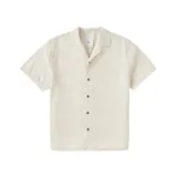 Camisa de manga corta color blanco hueso, con cuello solapa y cierre frontal con botones marrones.