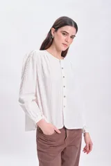 Blusa color crudo con textura, mangas largas abullonadas y cierre frontal con botones.