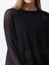 Poncho negro de tejido calado con lurex, terminación asimétrica y cuello redondo.