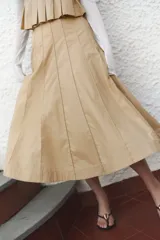 Pollera midi color beige con tiro alto, diseño circular y rayas cosidas. Presenta cierre oculto y corchete en un lateral. Sin forrar.