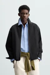 Sobrecamisa color crema de tejido técnico ligero, corte regular fit, cuello solapa, manga larga con puño abotonado, bajo ajustable con elástico en laterales y cierre frontal con cremallera.