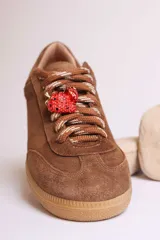 Zapatillas bajas marrones de gamuza con cordones y detalle de aplique de fresa en los cordones.
