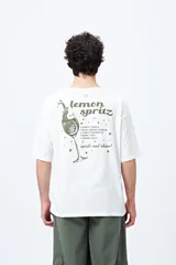 Remera blanca de corte holgado con mangas cortas y cuello redondo. Estampado pequeño en el frente con la frase "Spritz and Shine" en verde.