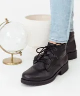 Bota acordonada color marrón claro de cuero, con suela de goma color beige y cordones finos blancos.