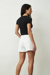 Short de jean blanco con roturas y terminación desflecada.