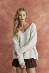 Sweater tejido color crudo, de corte holgado y escote en V con bordado en contraste.