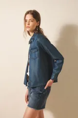 Camisa de manga larga confeccionada en tencel, color azul denim, de corte clásico, con cuello camisero, bolsillos en el frente y botones metálicos.