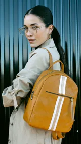 Mochila color beige con diseño capitoneado, bolsillo frontal con cierre, asa de mano y correas regulables.