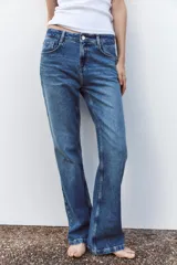 Pantalón de jean azul de tiro alto, corte bootcut, con cinco bolsillos, cierre frontal con cremallera y botón.