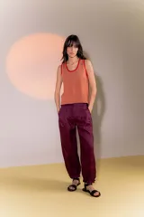 Pantalón de lino color borgoña, de corte amplio, con tiro medio, pretina ancha con doble abotonadura, bolsillos laterales, pinzas en el frente y ruedo con presilla para usar recto o fruncido al tobillo.