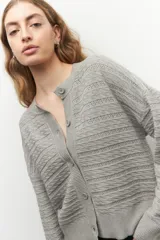Cardigan corto de punto con tramas en color gris, con mangas elastizadas y cierre de botones.