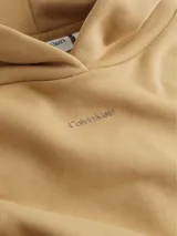 Buzo color beige de corte holgado, con capucha y logo de Calvin Klein bordado en el pecho.