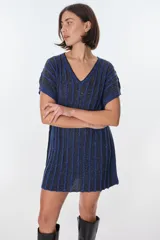 Vestido corto de tejido de punto con cuello V y mangas cortas, con diseño de rayas verticales en tonos azul oscuro y negro, con hilos de lurex que le dan brillo. Se ajusta a la cintura con un lazo fino negro.