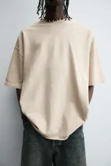 Camiseta color beige de corte holgado, cuello redondo y manga corta.