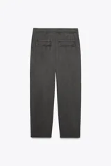 Pantalón gris oscuro de tiro alto con cintura elástica, bolsillos delanteros y falsos bolsillos con solapa en la espalda. Cierre frontal con cremallera y botón.