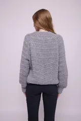 Cárdigan tejido a crochet color gris, con cuello redondo, mangas abullonadas, botones grandes y terminaciones acanaladas.