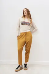 Pantalón de tiro medio color mostaza, de calce holgado que se ajusta al tobillo. Tiene cintura elastizada con tiras regulables.