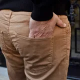 Pantalón de vestir negro, de corte recto, con bolsillos laterales y traseros. Se ajusta a la cintura con cinturón de cuero marrón.