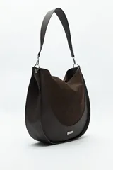 Bolso tipo hobo de cuero sintético negro con panel frontal de gamuza. Tiene correa de hombro ajustable y logo metálico plateado.