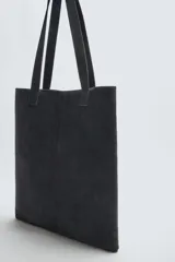 Bolso tipo shopper fabricado en piel con acabado serraje color gris oscuro. Tiene compartimento principal abierto con un bolsillo interior con cierre. Cuenta con dos asas de mano fabricadas en piel.