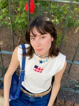 Remera blanca sin mangas de algodón con un bolsillo en el pecho con la bandera de Uruguay.