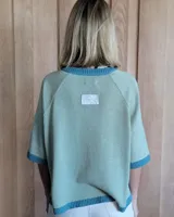 Buzo de punto color verde kiwi con cuello, puños y ruedo en azul.