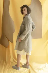 Camisa larga color crema con rayas verticales finas en gris, con botones dorados y bolsillo plaque en la delantera.