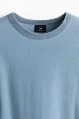 Remera celeste de corte estándar, confeccionada en tejido de punto de algodón de peso medio, con cuello redondo ribeteado acanalado y bajo recto.