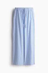 Pantalón de corte holgado en algodón a rayas verticales azules y blancas. Modelo de tiro alto con cintura elástica fruncida y cordón para ajustar. Piernas anchas con bolsillos laterales discretos.