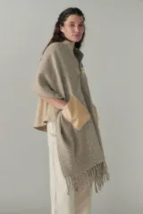 Chal de lana fina sin teñir, con calce en hombros, abrochadura con alamar de fieltro, bolsillos de cuero y terminación con flecos. Diseño exclusivo de Don Baez, hecho en Uruguay.