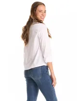 Camisa blanca de manga 3/4 con puños doblados, cuello en V y cierre de botones frontal. Presenta dos bolsillos delanteros con detalles de tachas metálicas.