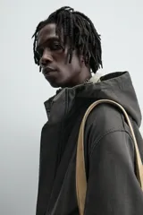 Parka relaxed fit color negro confeccionada en tejido de lino que repele el agua. Tiene cuello con capucha ajustable, mangas largas con puños abotonados, bolsillos frontales con solapa y cierre frontal con cremallera oculta por solapa con botones a presión.