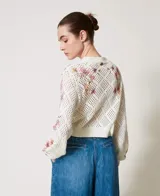 Cárdigan de punto calado color crema con estampa floral en tonos rosa y lila, escote en V y cierre frontal con botones.