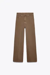 Pantalón de jean color marrón, de tiro alto, corte wide leg y relaxed fit. Cuenta con bolsillos delanteros y traseros, trabillas en la cintura, cierre frontal con cremallera, botón interior y gancho metálico.